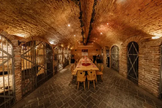 Langer Gewölbegang des Weinbunkers mit Gittertoren und gedeckter Tafel