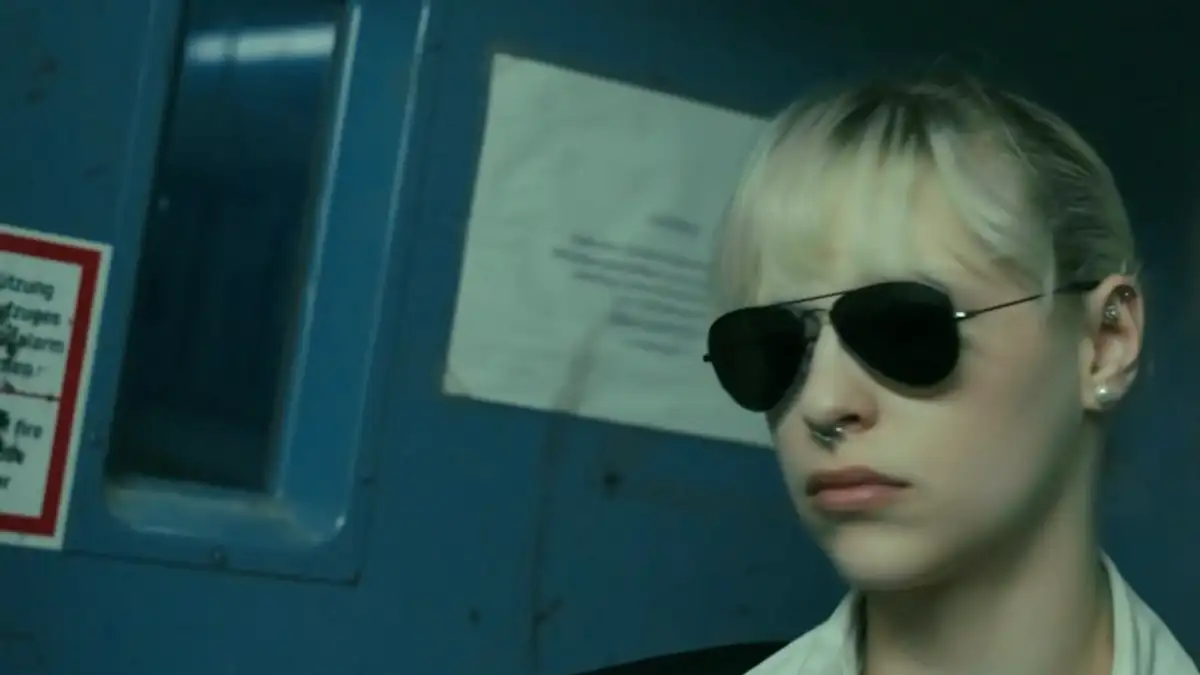 Agentin mit Sonnenbrille vor einer blauen Stahltür – Standbild aus einer Mission von Secret Mission