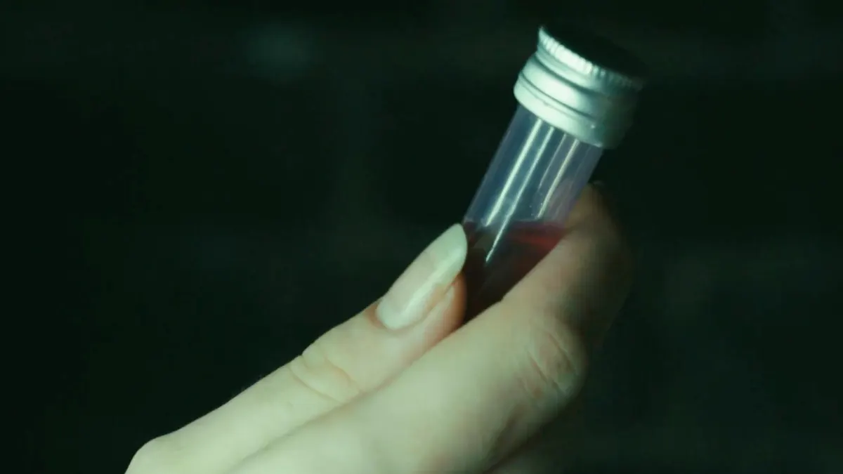 Une main tient un tube scellé contenant un liquide rouge – une pièce à conviction du film sur la mission NOVEX-3